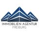 Logo der Immobilien Agentur Freiburg mit blauen stilisierten Gebäuden.