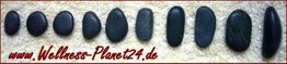 Dunkle, flache Steine in einer Linie auf beigem Untergrund, mit der Aufschrift "Wellness-Planet24.de".