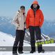 Zwei Personen in Winterkleidung auf einem schneebedeckten Berg, Alpen im Hintergrund.