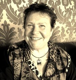 Eine lächelnde Person vor gemustertem Hintergrund in einem Porträtfoto.