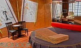 Stanza elegante con letto rotondo, specchi e tavolino con due sedie. Quadri astratti alle pareti.