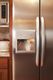 Stainless steel fridge with ice dispenser beside a wood-finished kitchen counter.