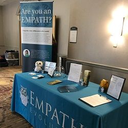 Exhibit table with "Empath Evolution" banner and informational materials in a conference setting.