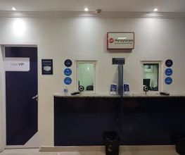 Balcão de atendimento com duas janelas, porta à esquerda e logo da MoneyGram acima do balcão.