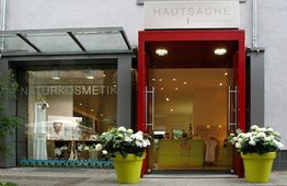 Geschäftseingang mit roten Rahmen, zwei gelbe Pflanzgefäße, Schaufenster mit "Naturkosmetik"-Schriftzug.