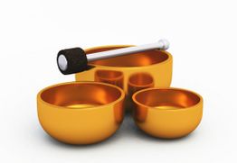 Drei goldene Klangschalen und ein Schlegel auf weißem Hintergrund.