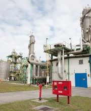 Indústria com tanques grandes e estrutura metálica sob céu nublado. Caixa vermelha em destaque.