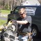 Person using a saw near a van with "Gutter Master" sign, on a sunny day.