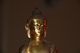 Goldene Buddha-Statue auf dunklem Hintergrund, leicht von der Seite beleuchtet.