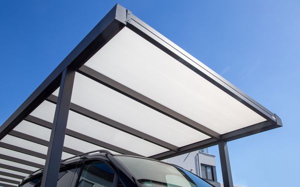 Ein Carport aus einer Stahlkonstruktion. Darunter steht ein schwarzer PKW.