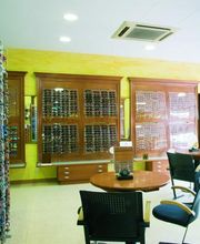 Tienda de óptica con estantes de gafas y sillas para atención al cliente.