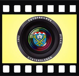 Kameralinse mit Logo und Text "Fotofreunde Güntersleben" auf gelbem Hintergrund.