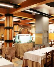 Restaurante rústico con mesas blancas y barriles grandes de madera en las paredes.