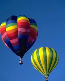 Zwei bunte Heißluftballons vor klarem, blauem Himmel.