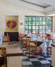 Restaurante acogedor con mesas decoradas y obra de arte colorida en la pared.