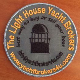 Rond logo Lighthouse Yacht Brokers met tekst en vuurtorenafbeelding op houten achtergrond.