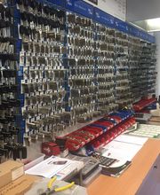 Wand voller Schlüssel vor Werkbank mit Werkzeugen und Papieren in einem Schlüsseldienst.