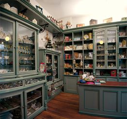 Antiker Laden mit grünen Regalen, gefüllt mit Spielzeug, Sammlerstücken und Geschenkartikeln.