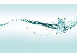 Ein klarer Wasserstrahl spritzt gegen einen hellen Hintergrund, Blasen steigen auf.