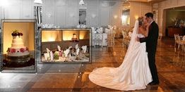 Bride and groom dancing at a wedding, with cake and table settings in the background.