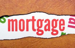 Torn paper revealing the word "mortgage" in red on a textured brown background.