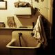 Rustic sink with towels and shelves cluttered with jars and tools on a worn wall.