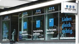 Fassade eines Geschäfts mit blauen und weißen Schildern und Slogans wie "Lieber. gleich. richtig."