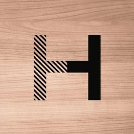 Letter H met zwart-witte lijnen en massieve rechterkant op een houten achtergrond.