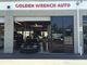 Exterior view of Golden Wrench Auto shop with open garage and parked car.