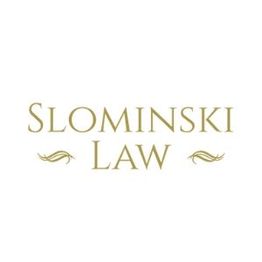 "Slominski Law logo with elegant gold text and decorative accents on a white background."