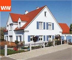 Weißes Haus mit rotem Dach, blauen Fensterläden und gepflegtem Garten. Straße im Vordergrund.