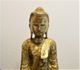Eine goldene Buddhastatue vor einem neutralen Hintergrund.
