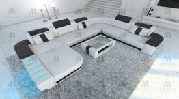 Wohnzimmer mit großer, moderner, grauer Eckcouch und passendem Couchtisch auf einem Teppich.