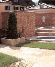 Hof mit Ziegelmauern, erhöhtem Brunnen und gepflegtem Pflaster.