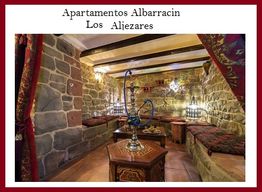 Sala rústica con paredes de piedra y decoraciones árabes, con un hookah en el centro.