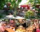 Gartenrestaurant mit Terrasse, zwei ältere Personen beim Essen, Buffet mit zwei Gästen.