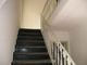 Scala interna con gradini neri e ringhiera bianca decorata. Pareti chiare intorno.