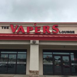 Storefront of "The Vapers Lounge" with large red letters and glass windows.
