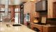 Rustic kitchen with wooden cabinets, granite island, and modern appliances, overlooking snowy trees.