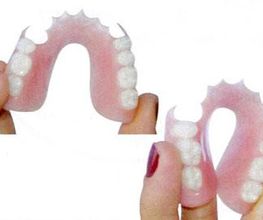 Dentiere flessibili tenute in mano, con base rosa e denti bianchi.