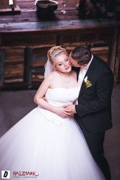 Ein Brautpaar umarmt sich liebevoll bei ihrer Hochzeit in einem rustikalen Raum.