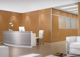 Recepção moderna com balcão metálico, cadeira branca e parede de madeira clara.