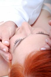 Person receiving facial acupuncture with thin needles near the brow.