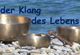 Drei Klangschalen auf Kieseln am Wasser, Text: "Der Klang des Lebens".