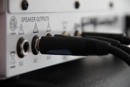 Rückseite eines Verstärkers mit angeschlossenen Audiokabeln an Lautsprecherausgängen.