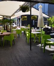 Außenterrasse mit grünen Stühlen und Sonnenschirmen in einem modern gestalteten Café.