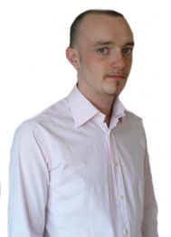 Mann im rosa Hemd mit kurzem Haar, schaut leicht zur Seite.