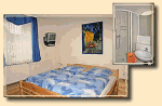 Schlafzimmer mit Doppelbett, blauem Vorhang, Fernseher an der Wand und kleinem Badezimmer mit Dusche.