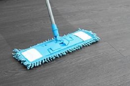 Blue mop cleaning a dark wooden floor.