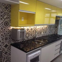Cozinha moderna com azulejos geométricos, armários amarelos e bancada preta.